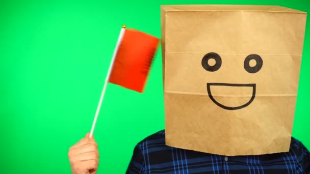 Portrait of man with paper bag on head waving Albanian flag with smiling face against green background. — Stock Video