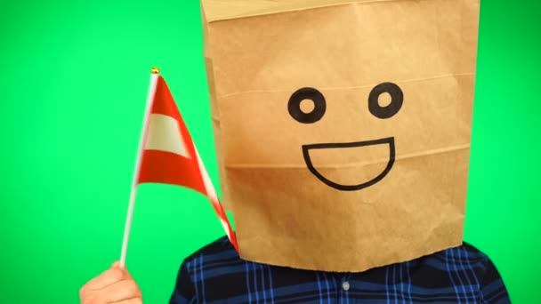 Πορτρέτο του ανθρώπου με χάρτινη τσάντα στο κεφάλι κυματίζει αυστριακή σημαία με χαμογελαστό πρόσωπο σε πράσινο φόντο. — Αρχείο Βίντεο