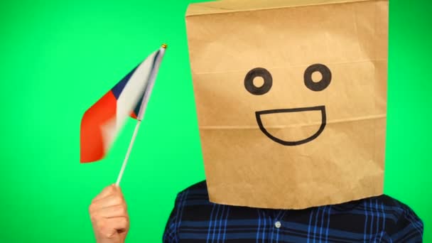 Portret mężczyzny z papierową torbą na głowie machającego czeską flagą z uśmiechniętą twarzą na zielonym tle. — Wideo stockowe