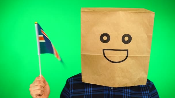 Портрет людини з паперовим мішком на голові розмахуючи ісландським прапором з посмішкою обличчя на зеленому тлі. — стокове відео