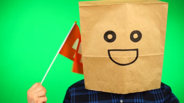 Retrato de hombre con bolsa de papel en la cabeza ondeando bandera suiza con la cara sonriente sobre fondo verde. — Vídeos de Stock