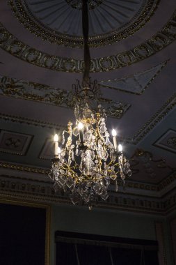 Tavanın altında antik metal bir avize var.