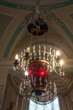 Tavanın altında antik metal bir avize var.