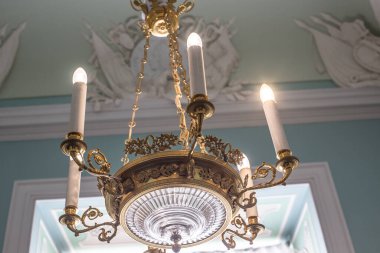 Tavanın altında antik metal bir avize var.