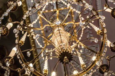 Tavanın altında antik metal bir avize var.