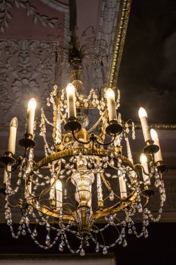 Tavanın altında antik metal bir avize var.