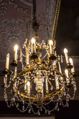 Tavanın altında antik metal bir avize var.