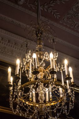 Tavanın altında antik metal bir avize var.