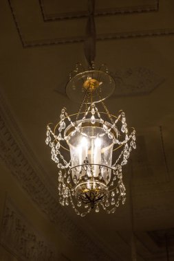 Tavanın altında antik metal bir avize var.