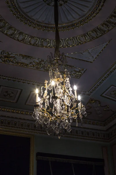 Tavanın altında antik metal bir avize var.