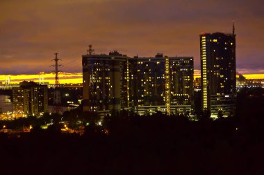 Şehrin kenar mahallelerindeki yeni binaların üzerinde gün batımı 