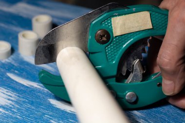 Tesisatçı lehimlemeden önce metal-plastik boruları keser. Kapat.