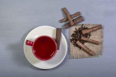 Bir fincan tarçın çayı, tarçın çubukları ve karanfil taneleri.