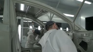 Checkman boya işleminden önce arabaların montajını kontrol ediyor. Araba üretim fabrikası.