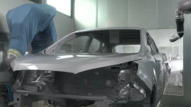Robot silah spreyi araba imalat fabrikasında bir araç cesedi boyuyor.