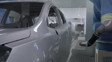 Robot silah spreyi araba imalat fabrikasında bir araç cesedi boyuyor.
