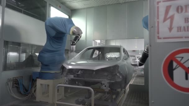 자동차 제조 공장에서 자동차의 몸체에 페인트를 뿌리는 로봇 팔 — 비디오