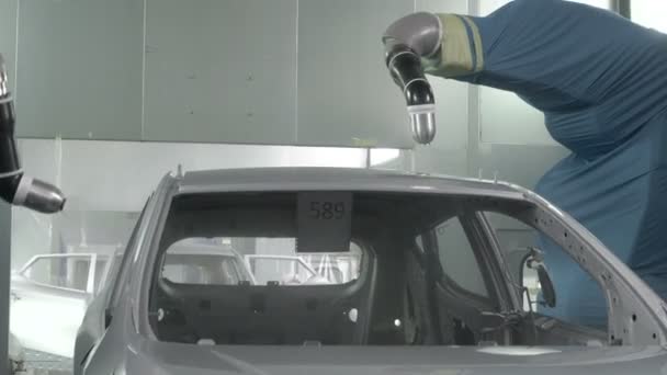 Роботизированные руки распыляют краску на кузов автомобиля на автозаводе — стоковое видео