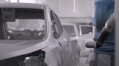 Robot silah spreyi araba imalat fabrikasında bir araç cesedi boyuyor.