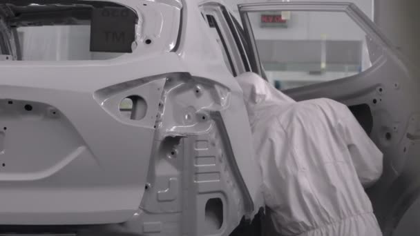 Pintura de piezas de vehículos en cabina sprcial. Fábrica de fabricación de automóviles. Dos pintores rocían pintura blanca en un coche de choque. — Vídeos de Stock