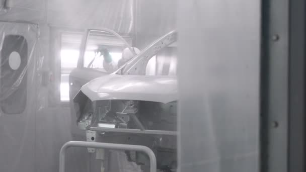 Lackieren von Fahrzeugteilen in der Sprintzentrale. Automobilfabrik. Maler sprüht weiße Farbe auf Autoscooter. — Stockvideo