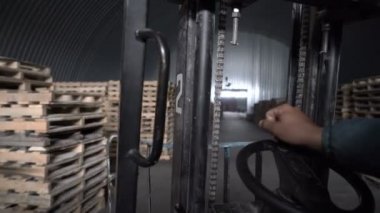 Elektirik forklifti işçiler kullanıyor. Yükleme sırasında kutularla yükleyici ve tahta palet.