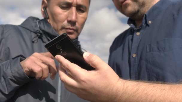 Podnikatel a agronomové pracují s pomocí agroaplikace na chytrém telefonu. Sklizeň ovsa zraje na poli. Smart ago business. — Stock video
