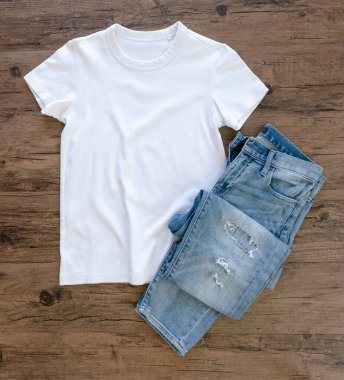 White T-shirt and jeans mock up flat lay on wooden background. Top front view