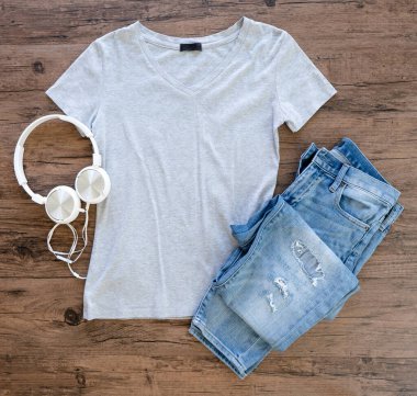 Grey T-shirt and jeans mock up  with headphone flat lay on wooden background. Top vie