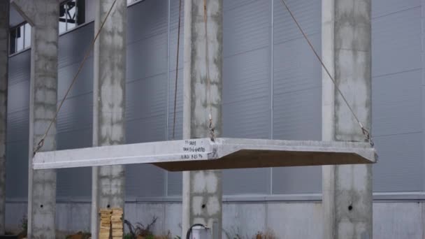 En kran lyfter en armerad betongplatta. Byggande av en stor anläggning. — Stockvideo