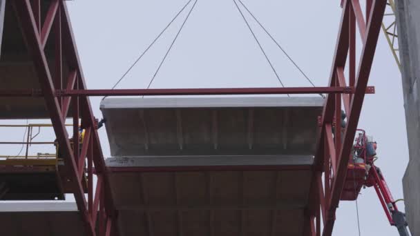 Werknemers gebruiken een kraan om een betonnen plaat op het dak van het gebouw te plaatsen. — Stockvideo