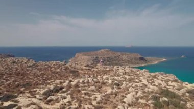 Hava görüntüsü. Yunan adası Girit 'teki güzel Balos Körfezi. Bir adam ve bir kadın güzel manzaralı bir uçurumun kenarında dururlar..