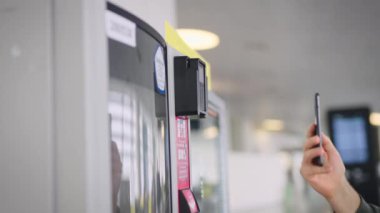 Çerçevede akıllı telefonu ve otomatı olan bir adam eli var. Adam kahvesini ve abur cuburunu ödüyor..