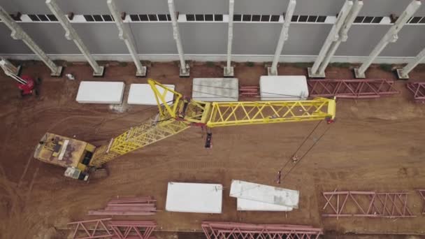 Vue aérienne. Une grue lourde sur un chantier soulève des dalles de béton de fer. — Video