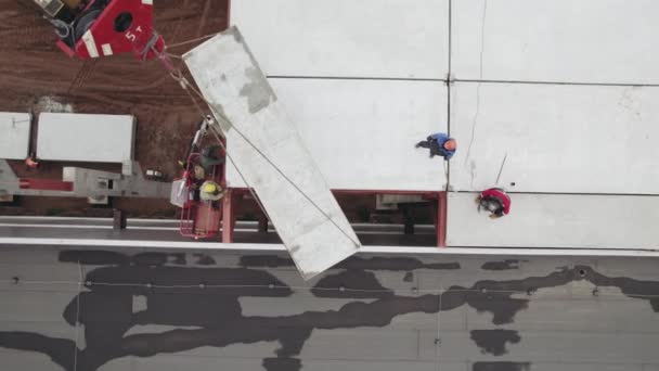 Vista aérea. Los trabajadores están montando el techo de un edificio industrial. Suelos de hormigón armado en la obra — Vídeo de stock