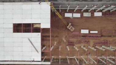 Hava görüntüsü. İşçiler bir sanayi binasının çatısını monte ediyorlar. İnşaat alanında güçlendirilmiş beton zemin