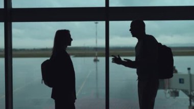Havaalanında bir çift uçak bekliyor. Bir kadın ve bir erkek pencerenin arkasında iletişim kuruyor..