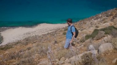 Bir adam, sırt çantalı bir turist, yamaçtan güzel Akdeniz 'e doğru gidiyor..