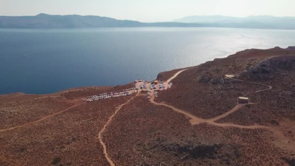 Вид с воздуха. Грязная дорога и парковка в бухте Балос. — стоковое видео