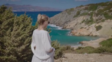 Beyaz elbiseli güzel bir kadın, nefis bir deniz manzarasının arka planında..