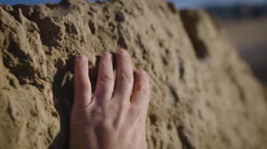 A mans hand touches the old stones of the fortress wall.