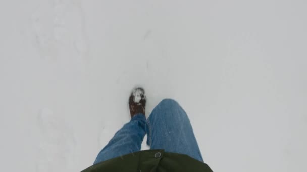 男性腿的头像。一个穿着时髦靴子的男人沿着白雪覆盖的人行道走着. — 图库视频影像