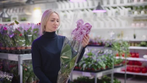Uma mulher escolhe uma orquídea para jardinagem em casa. Flores frescas no interior. — Vídeo de Stock