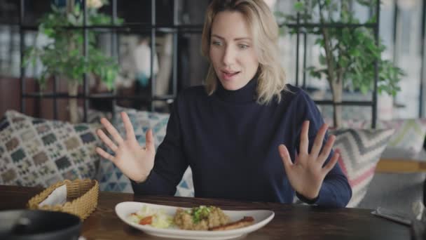 Una rubia agradable en un restaurante está feliz de comer un plato de pescado y arroz. Mujer divertida se alegra de que le trajeron comida — Vídeos de Stock