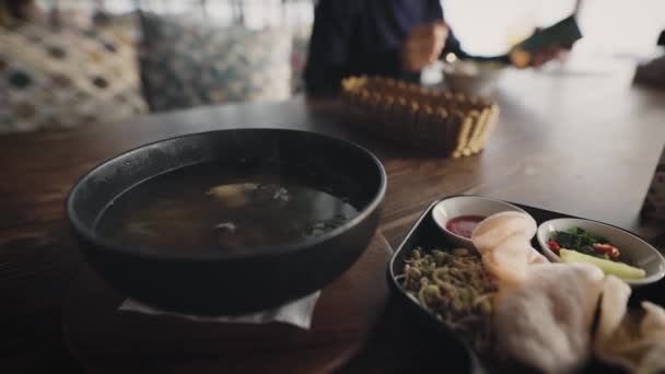 Een man in een restaurant bestelde Aziatische pho bo soep. Pan-Aziatische keuken — Stockvideo