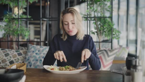 Uma loira agradável em um restaurante está feliz em comer um prato de peixe e arroz. Mulher engraçada está feliz que ela foi trazida comida — Vídeo de Stock