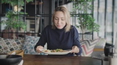 Bir restoranda hoş bir sarışın bir tabak balık ve pilav yemekten mutlu olur. Komik kadın yemek getirildiği için çok mutlu.