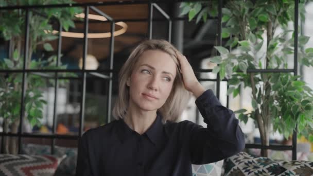 Porträt einer attraktiven Blondine. Junge Frau in einem modernen Café — Stockvideo