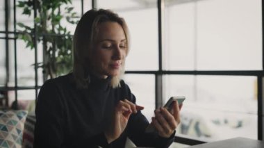 Çekici sarışın kadın bir kafede akıllı telefon kullanıyor. Bir kadın arkadaşlarıyla ve meslektaşlarıyla sohbet ediyor..