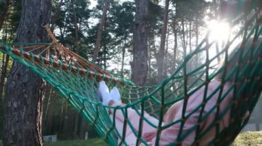 Bir hamakta yatan ve yeşil bir ormanda dinlenen bir kadın..